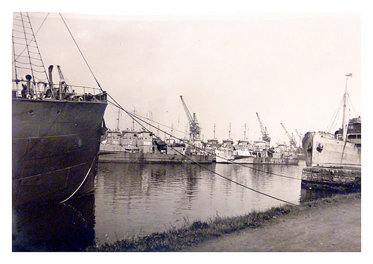 1943-4 - A photograph taken from the southern side of the dock toward the LST's moored up in regimental rows against the northern quay wall. 