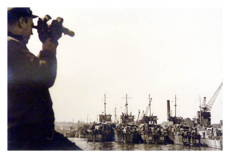 A US officer takes a sighting whilst in the Penarth Dock are many LST's.