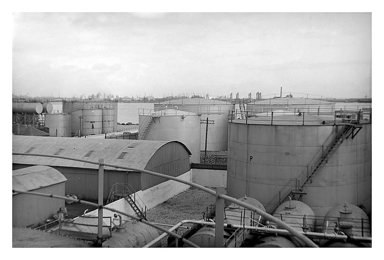 mid-1950's to early 1960's - A photograph of the oil storage tanks situated at the Ferry Road side of the River Ely Tidal Harbour. A view of the extensive facility from the top of one of the tanks. Distant are the docks at Cardiff.