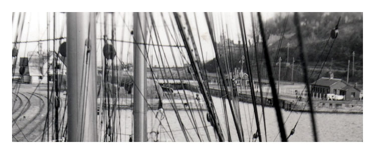 A view aft through the shrouds of the tall ship 'Pamir' with the swing bridge just peeping out from behind the quonson huts.